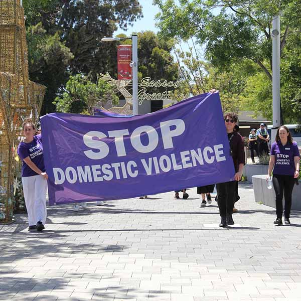 Two people holding a large cloth sign that says "Stop Domestic Violence."